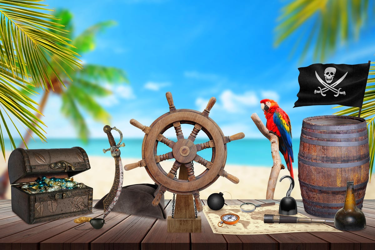 Pirate table with ship wheel, treasure, map, rum, compass.